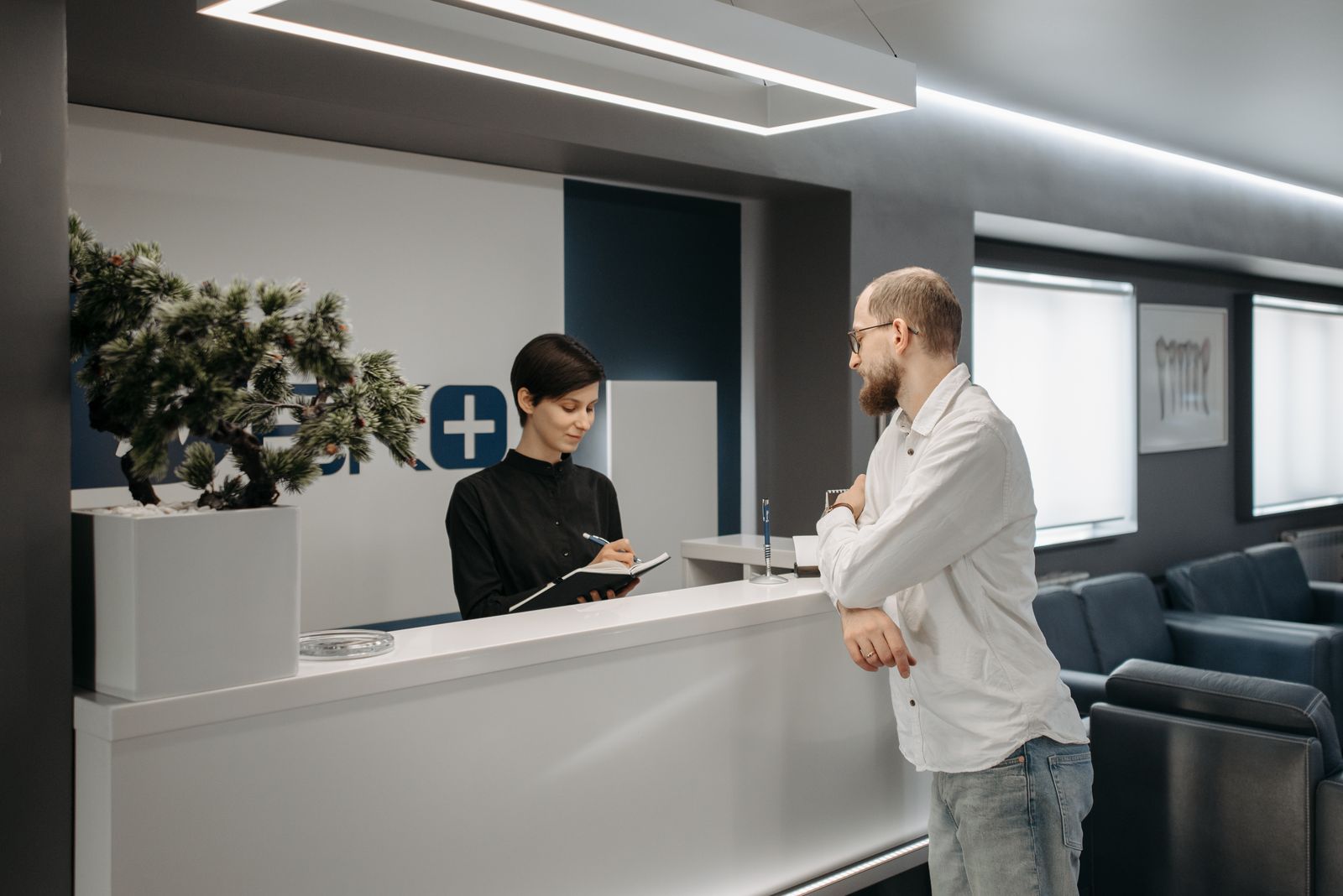 Paciente conversando com a recepcionista no balcão de uma clínica moderna